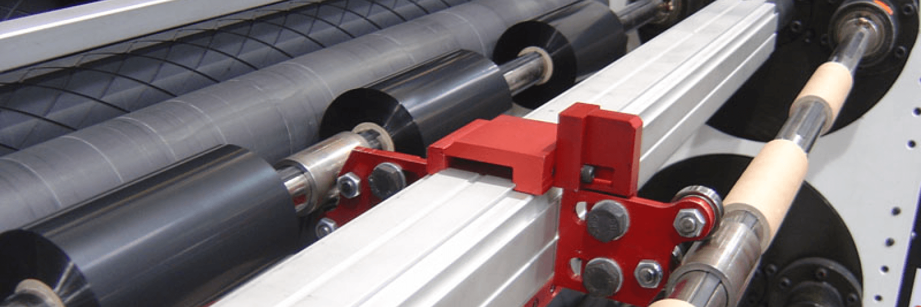 Close-up of a printing press mechanism with rollers and a red clamp.
